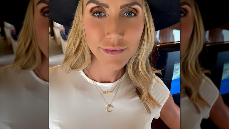 Lara Trump poses for a selfie while wearing a white t-shirt and a necklace that says "MAHA"
