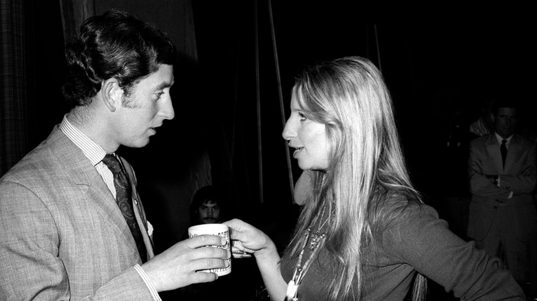 King Charles talking to Barbra Streisand as they hold a mug together
