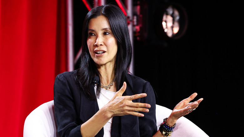Lisa Ling talking and gesturing with her hands while seated in a white chair.