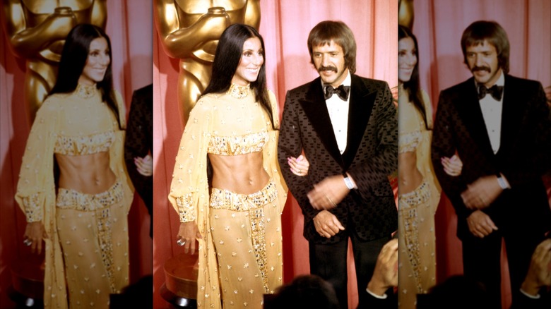 Sonny and Cher pose in front of an Oscars statue