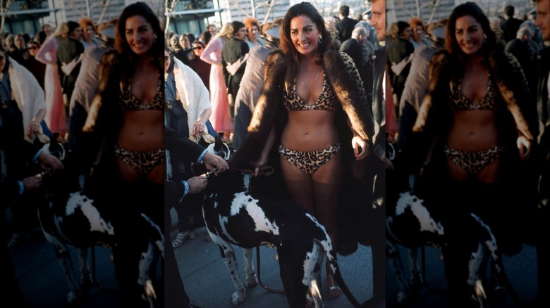 Edy Williams walks in a leopard-print bikini with dog