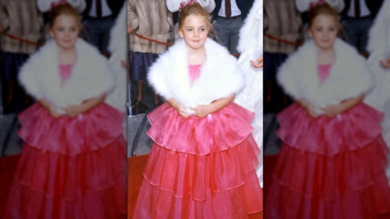 Drew Barrymore in pink dress white fur stole and pearls with a pink bow in her hair