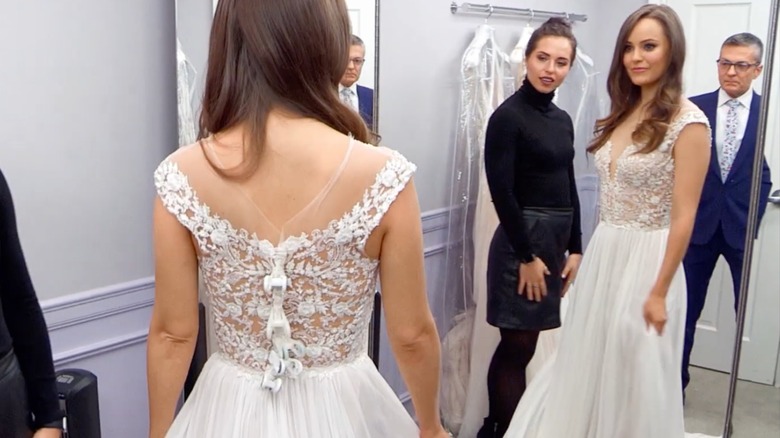 Tanya Lehoux looking in the mirror in a wedding dress with Randy Fenoli