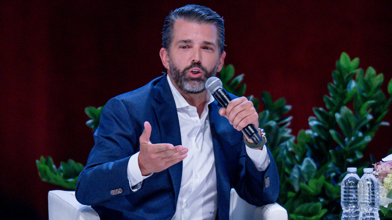 Donald Trump Jr. speaking over a microphone