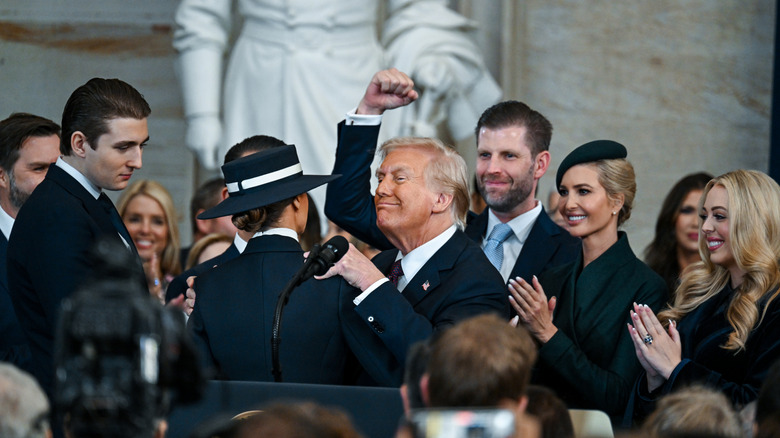 Donald Trump fist pumping the air at his 2025 inauguration, surrounded by his family