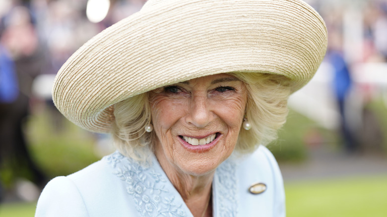 Close up of Queen Camilla wearing a straw hat at an event in 2025
