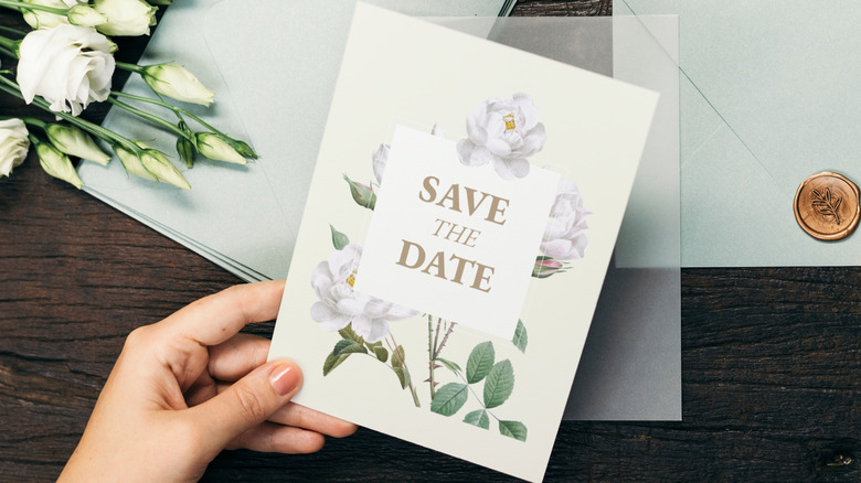 Person holds save the date card