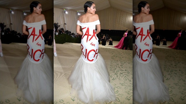 Alexandria Ocasio-Cortez smiles while showing off the back of her dress