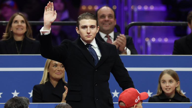 Barron Trump waving in a suit surrounded by people