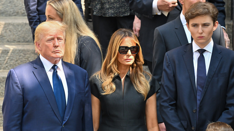 Barron Trump standing with Melania and Donald Trump looking serious