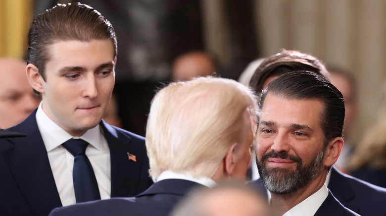 Barron Trump biting his lip while Donald Trump speaks to Donald Trump Jr.