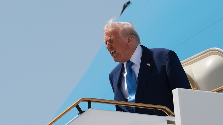 Donald Trump standing at the top of the Air Force One steps, shouting.