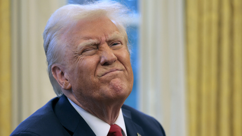 Donald Trump winking his eye while sitting behind his desk inside the Oval Office.