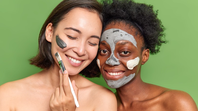Two women applying face masks