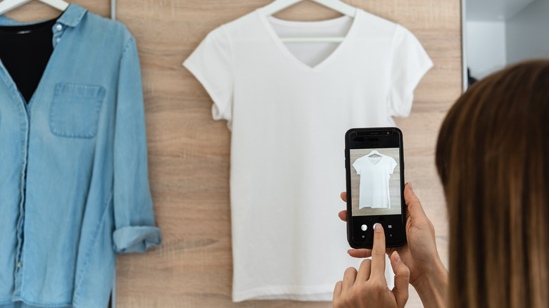 Woman taking photo of displayed clothes