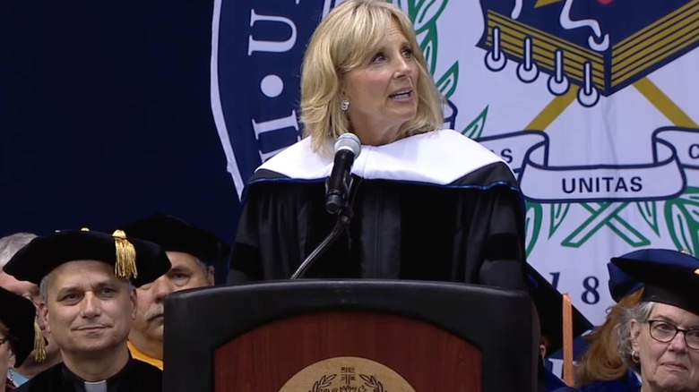 Pope Leo XIV sitting behind Jill Biden during her 2014 Villanova University commencement speech