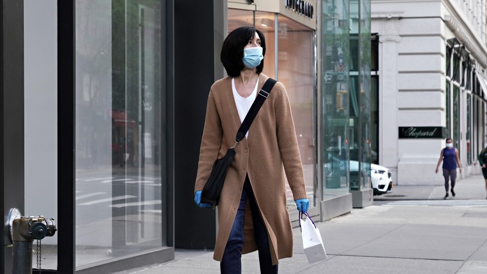 Person walking down the street with mask and coat