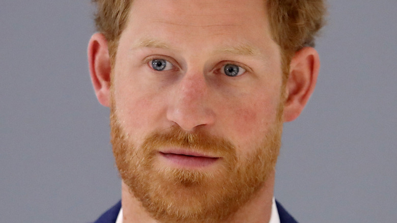 Prince Harry grimacing in a white shirt