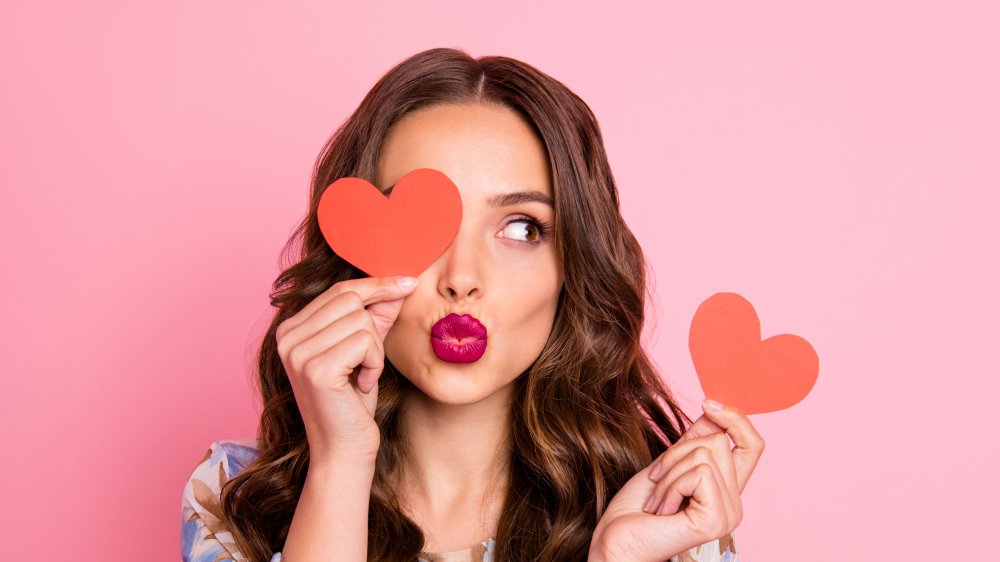 brunette with a pout and heart cutouts in hand