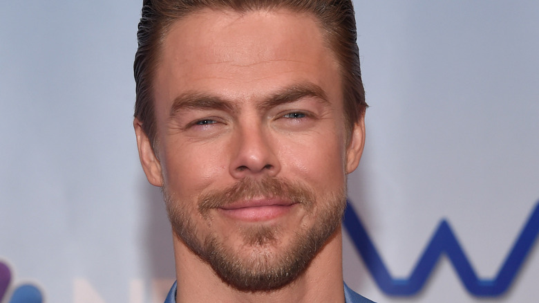 Derek Hough smiling on the red carpet.