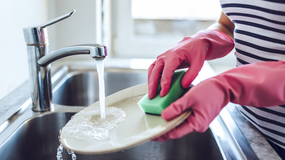 Person washing dishes in pink gloves