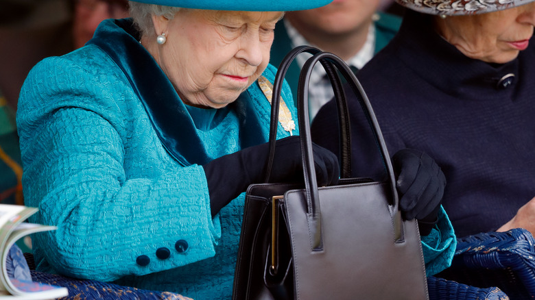 Queen Elizabeth II looking inside handbag