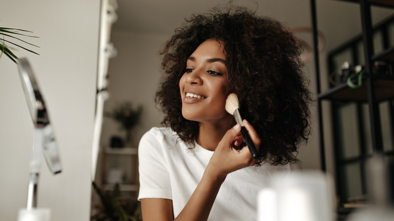 Woman using brush to apply makeup