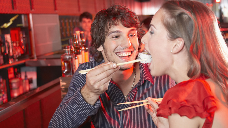 Man feeding a woman with chopsticks