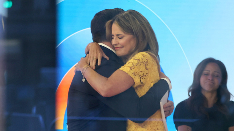 Savannah embracing her co-host as another colleague emotionally watches