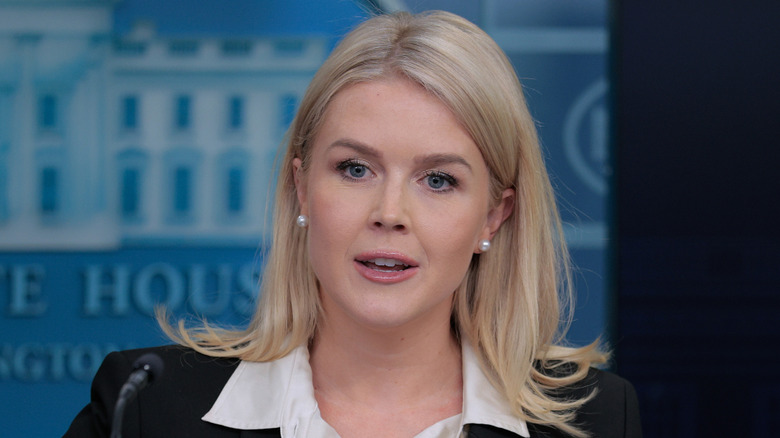 Karoline Leavitt wearing a black blazer and white collared shirt while speaking to reporters.