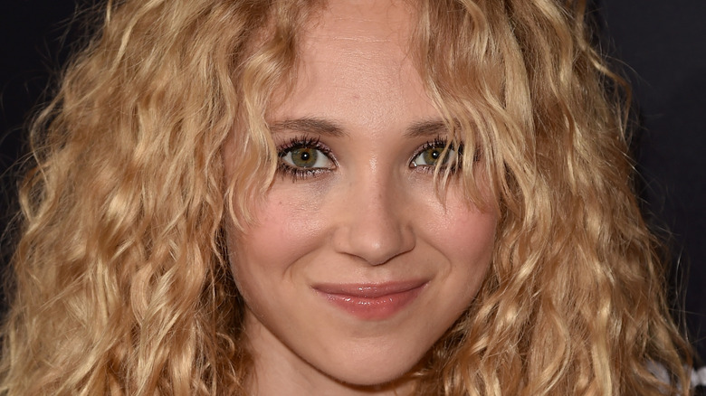 Juno Temple poses at an event with curly hair