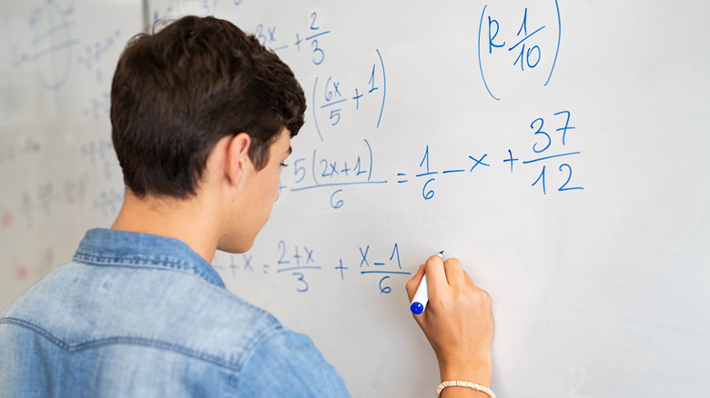 Person solving math equations on a whiteboard