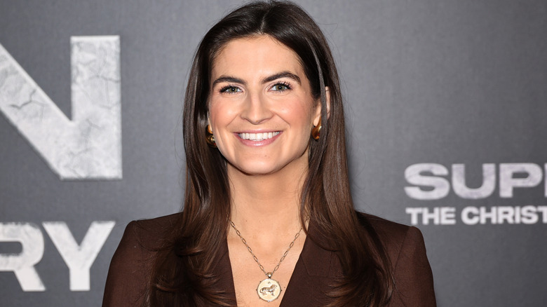 Kaitlan Collins smiling at camera, wearing medallion necklance and brown blazer