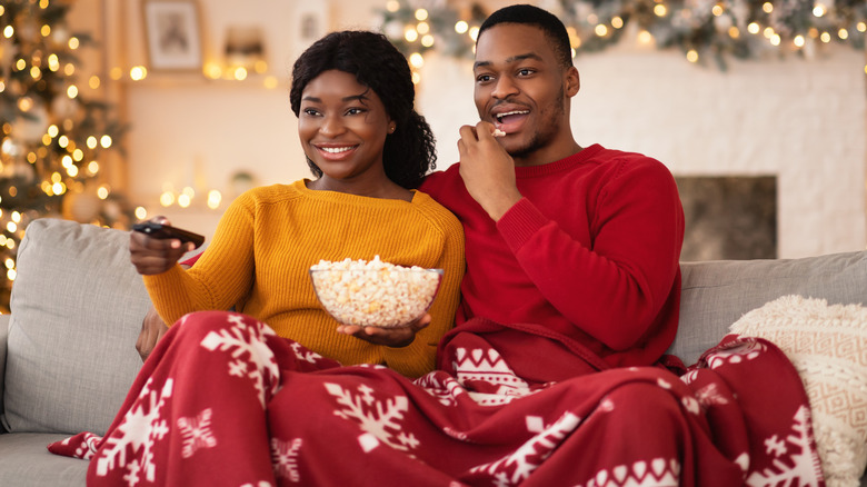 Couple with popcorn sits on a couch