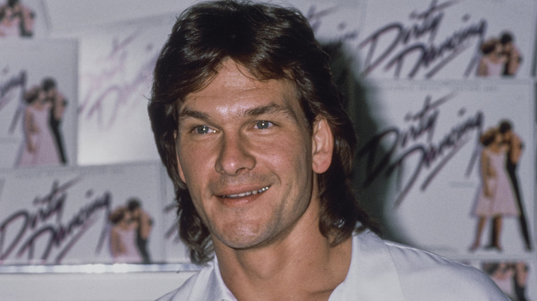 Patrick Swayze smiling in front of 'Dirty Dancing' soundtrack records