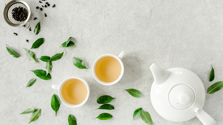 Cups of tea with white teapot and loose leaf tea