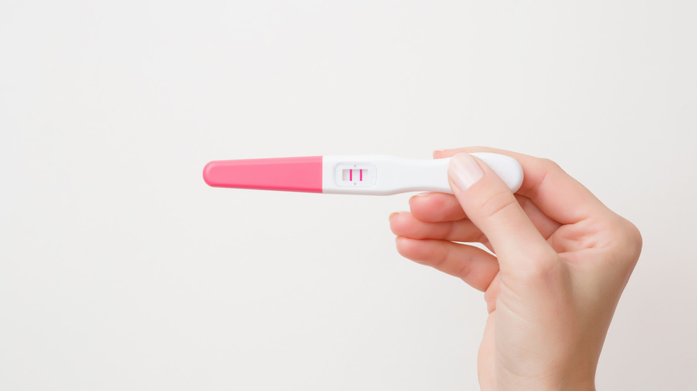 woman holding pregnancy test stick