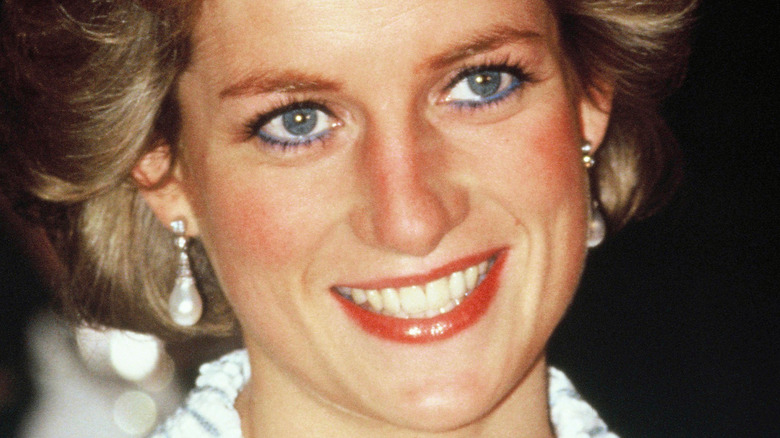 Princess Diana smiling and looking up while wearing pearl earrings