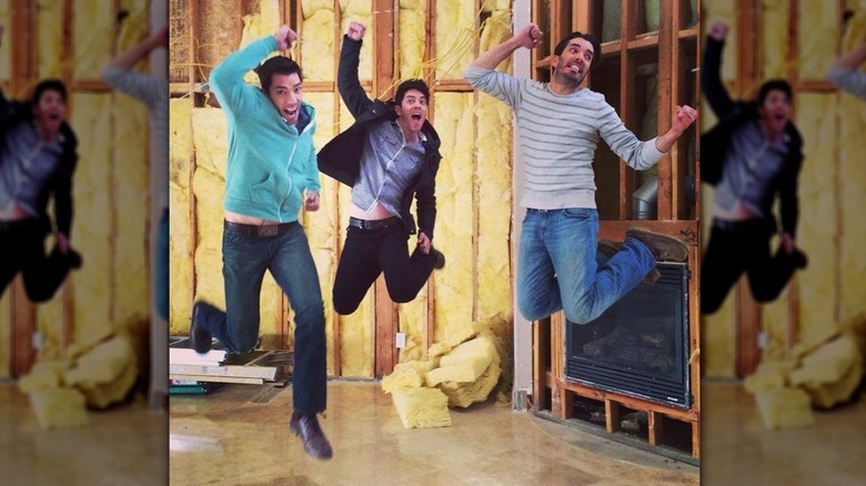 The Property Brothers and their third brother J.D. Scott jump in the air at a construction site