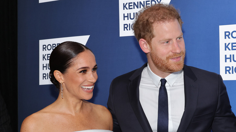 Meghan Markle and Prince Harry smiling at the cameras at a red carpet event