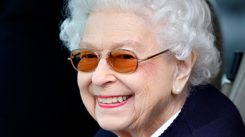 Queen Elizabeth wears sunglasses and smiles