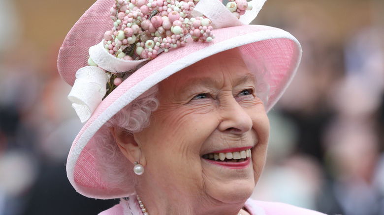 Queen Elizabeth II in pink hat laughing