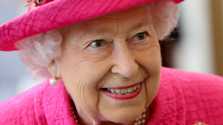Queen Elizabeth II smiling in a light-blue outfit with gloves