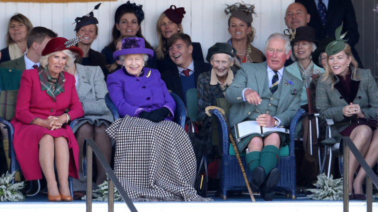 Queen Elizabeth smiling and watching the Braemar Games with Camilla and Prince Charles