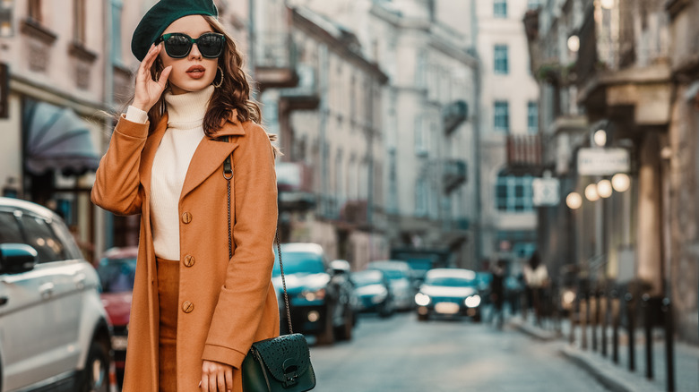 Woman wearing camel coat, sunglasses