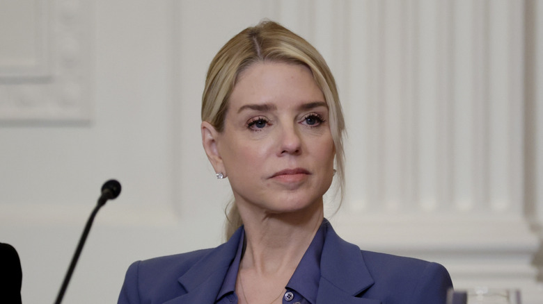 Pam Bondi looking intently ahead behind a microphone