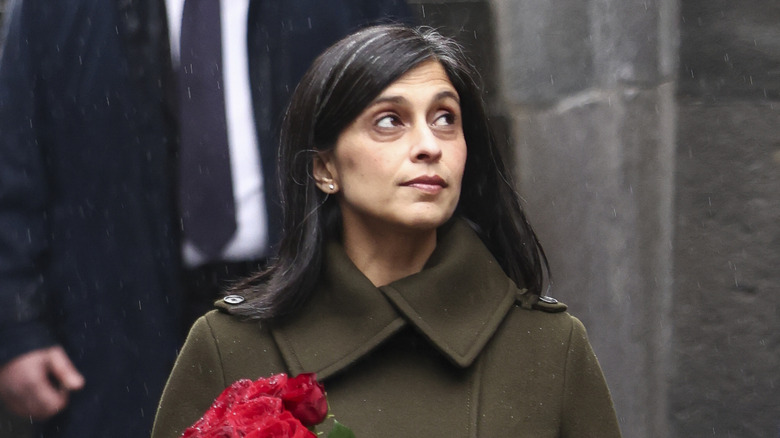 Usha Vance looks up walking through the rain holding a bouquet of roses