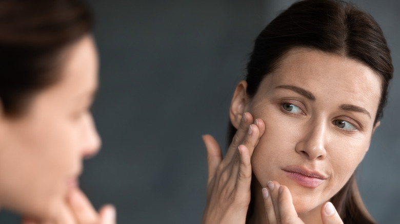 Woman examining her skin in the mirror