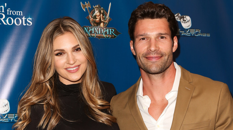 Natalie Pack wearing black and Aaron O'Connell wearing a brown suit