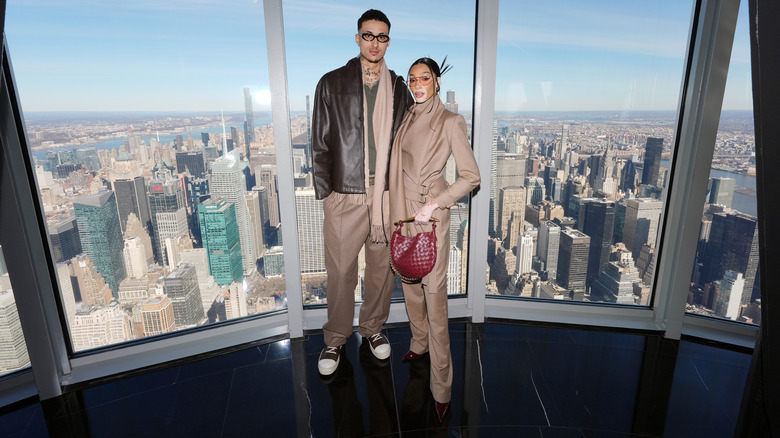 Kyle Kuzma and Winnie Harlow in front of a large window overlooking a city